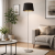 Nowoczesna lampa podłogowa w stylu minimalistycznym z czarnym abażurem i metalową podstawą. Idealna do salonu, sypialni lub biura – eleganckie oświetlenie, które podkreśla współczesne wnętrza i dodaje im przytulnego charakteru.