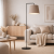 Nowoczesna lampa podłogowa w stylu minimalistycznym z eleganckim beżowym abażurem i smukłą czarną konstrukcją. Idealna do salonu w stylu skandynawskim lub modern. Zapewnia przytulne światło i podkreśla charakter wnętrza.
