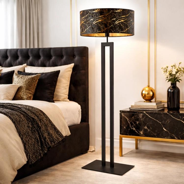 Nowoczesna lampa podłogowa w czerni ze złotymi akcentami w eleganckiej sypialni. Designerskie oświetlenie łączy styl glamour i minimalizm, zapewniając wyjątkowy klimat wnętrza oraz doskonały kontrast i funkcjonalność.