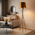 Nowoczesne wnętrze w stylu minimalistyczno-industrialnym z designerską lampą tripod w roli głównej. Elegancki salon łączy ciepłe barwy, metal i prostą formę, tworząc stylową i przytulną przestrzeń.