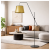 Nowoczesna lampa podłogowa z eleganckim złotym kloszem w designerskim wnętrzu. Stylowy czarny stelaż i minimalistyczna forma idealnie komponują się z salonem, dodając mu charakteru i ciepłego, nastrojowego oświetlenia.