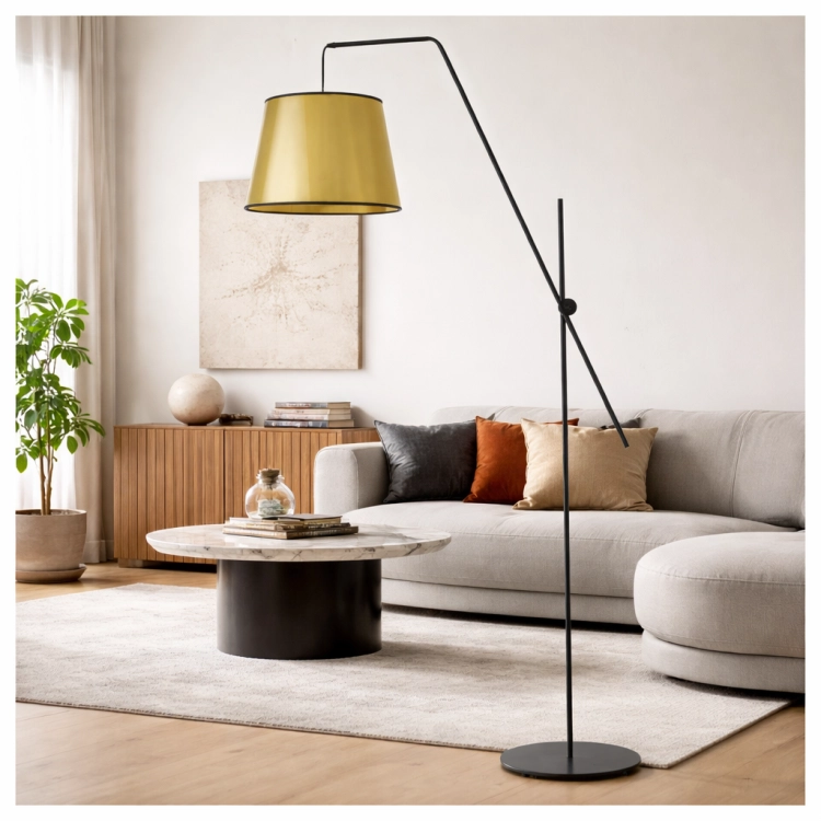 Nowoczesna lampa podłogowa z eleganckim złotym kloszem w designerskim wnętrzu. Stylowy czarny stelaż i minimalistyczna forma idealnie komponują się z salonem, dodając mu charakteru i ciepłego, nastrojowego oświetlenia.