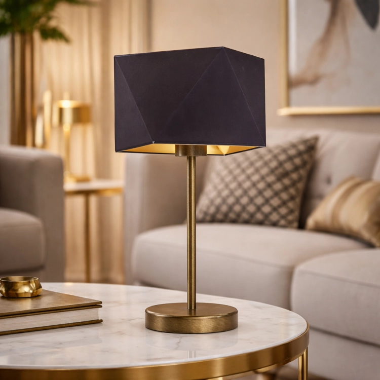Elegancka lampka stołowa z geometrycznym abażurem i złotym wnętrzem, która nadaje wnętrzu luksusowego charakteru. Smukła podstawa w kolorze starego złota oraz ciepłe światło tworzą wyjątkowy klimat w salonie, sypialni lub gabinecie.