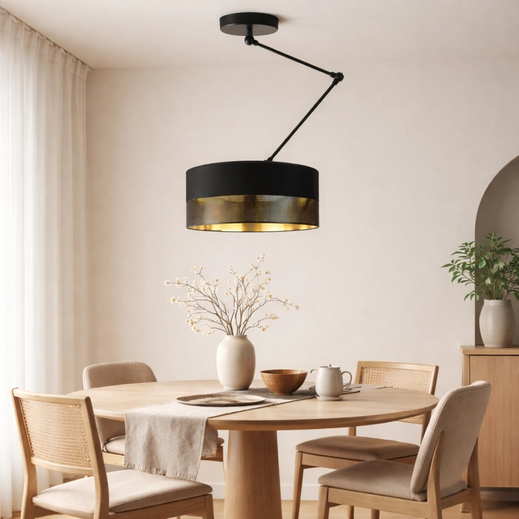 Nowoczesna lampa sufitowa o minimalistycznej, rzeźbiarskiej formie doskonale wpisuje się w styl japandi. Czarna, matowa konstrukcja z regulowanym ramieniem i perforowanym kloszem o złotym wnętrzu tworzy ciepłe, nastrojowe światło nad stołem.