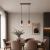 Nowoczesna lampa wisząca z podwójnym kloszem w odcieniu przydymionego szkła, idealna do jadalni lub salonu. Minimalistyczny design w stylu skandynawskim łączy elegancję z funkcjonalnością, zapewniając ciepłe, nastrojowe oświetlenie wnętrza.