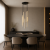 Nowoczesna lampa wisząca o wysokości 130 cm z eleganckimi, złotymi tubami zawieszonymi na czarnych przewodach. Idealna nad stół w jadalni lub do salonu, tworzy wyjątkowy klimat i podkreśla luksusowy, minimalistyczny charakter wnętrza.