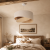 Lampa wisząca NAMI to designerska lampa sufitowa w stylu boho i japandi. Asymetryczny lniany abażur w beżowym kolorze subtelnie rozprasza światło, tworząc przytulną atmosferę w salonie, sypialni lub jadalni.